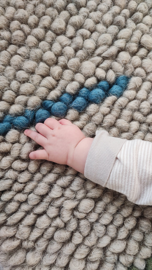 Child playing on the soft woolen Buzhok gray rainbow rug