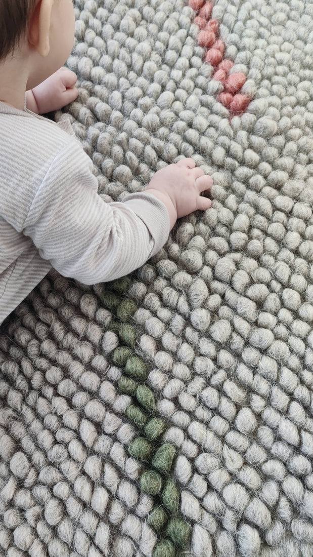 Child playing on the soft woolen Buzhok gray rainbow rug
