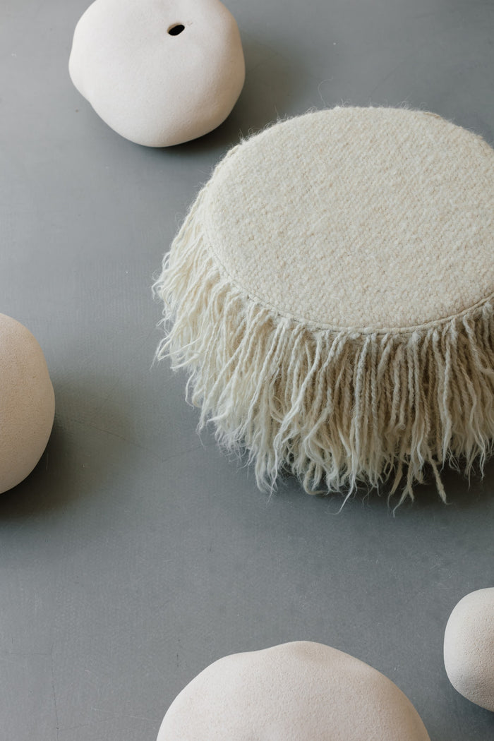 Minimalist wool pouf with elegant stitching details